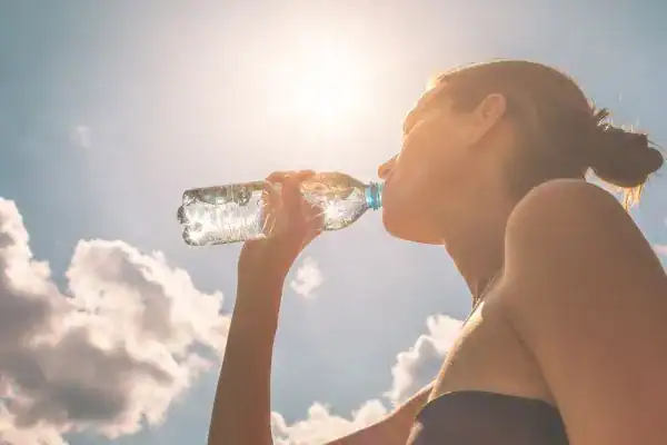Image of woman drinking water to hydrate Camberley after run.
