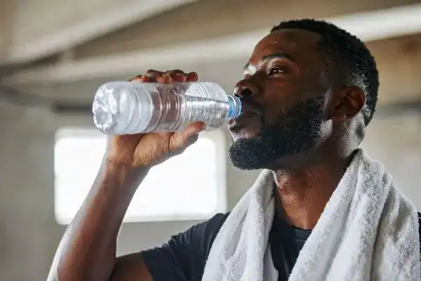 Image of man drinking water to improve hydration Camberley after work out.